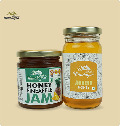 Two glass jars of Classic Himalayan honey products on a beige background: a jar of Honey Pineapple Jam and Acacia Honey.